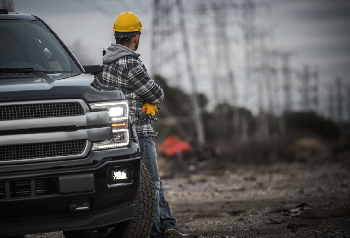 Construction worker standing against company vehicle